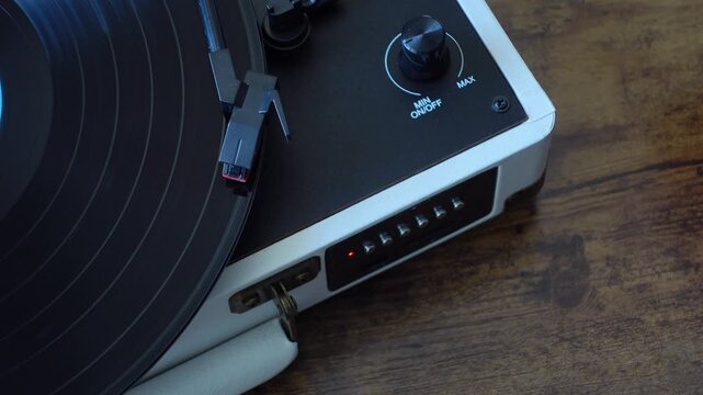 Vinyl record player needle dropping on spinning record, top view