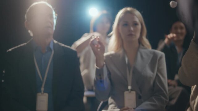 POV slowmo shot of diverse conference participants in formalwear throwing crumpled balls of paper at speaker, refusing to accept his scientific or business approach