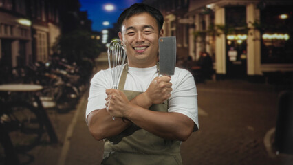 Chinese man holds whisk and cleaver on bustling urban street at night  pride passion creativity confidence. © Krakenimages.com