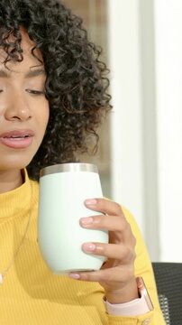 Vertical video: Noticing scent, smelling tumbler, woman in yellow top sipping to test aroma at home