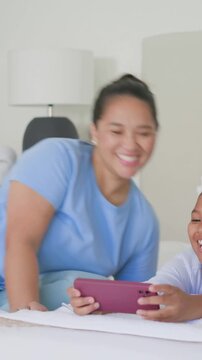 Vertical video: Reaching mom in pink picking phone, tapping gadget on bed, sharing clip with kids