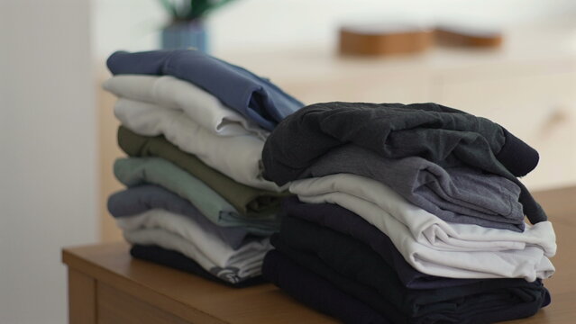 Folded clothes stacked neatly on wooden surface, symbol of domestic order, routine, and quiet care in everyday home life