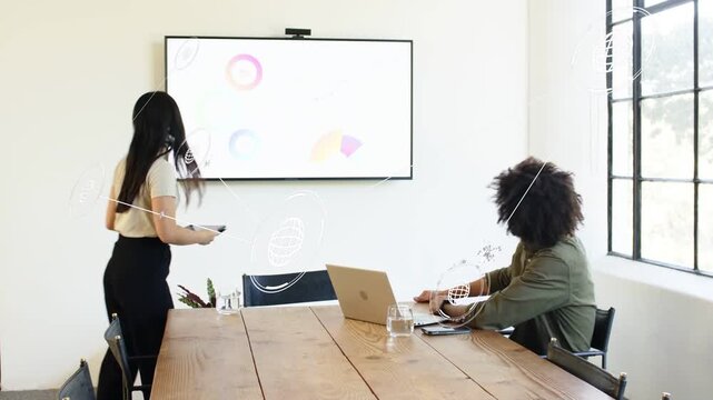 Woman checking tablet then standing, advancing circular chart graphics on wall display for business