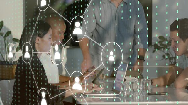 Lead pointing laptop starting network graph over screens while team tapping reviewing business data