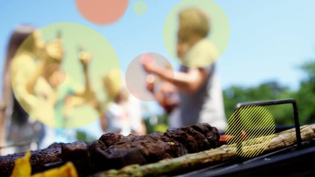 Grill shot showing skewers while friends raising bottles causing colorful circles at barbecue