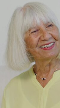 Vertical video: Smiling woman in yellow top beads turning right replying to offscreen voice at home