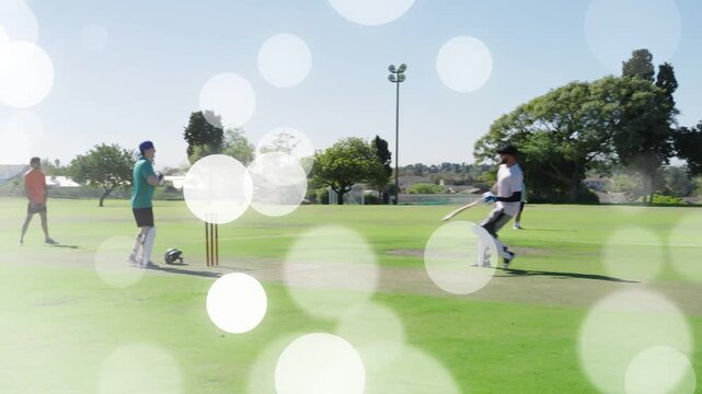 Male cricket batsman stepping striking ball and sprinting diving completing run bokeh over players