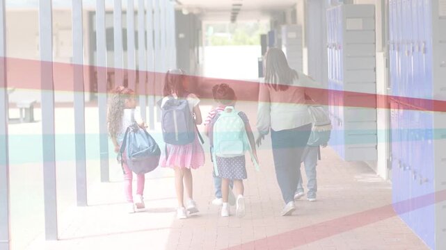 Teacher turning gesturing walking school hallway guiding children with backpacks toward bright exit