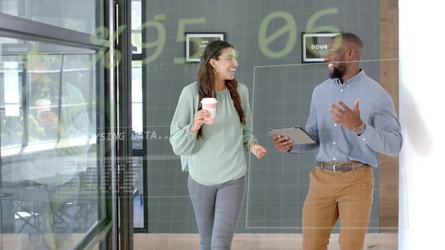Coworkers walking corridor, man pointing to tablet starting data boxes while discussing business