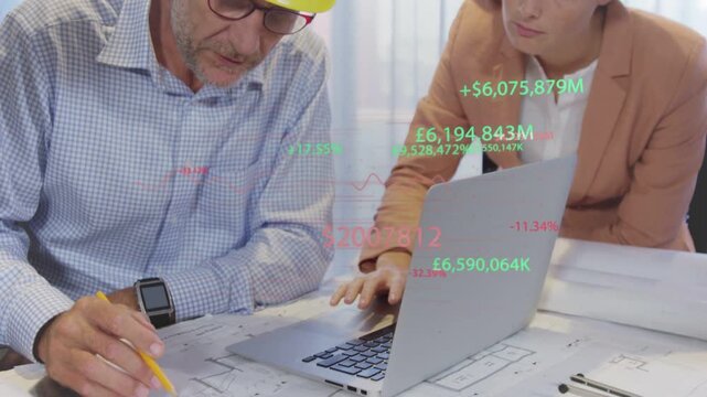 Architect marking plans while manager using laptop bringing cost overlays, donning helmets for site