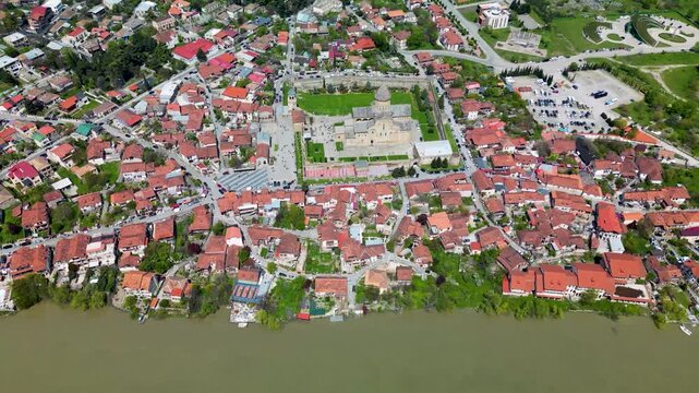 Aerial view of Mtskheta with red-roofed houses and the historic Svetitskhoveli Cathedral surrounded by river landscape. One of Georgia&rsquo;s oldest cities.