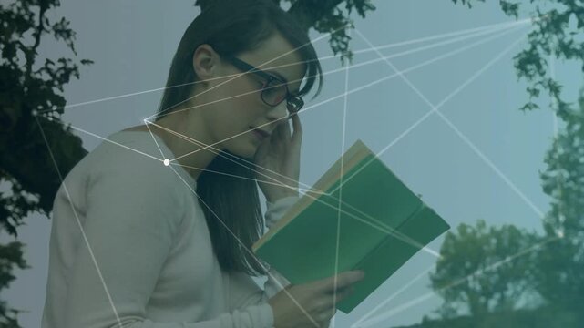 Reader reading green book under tree, looking down and animating node network overlay for edtech
