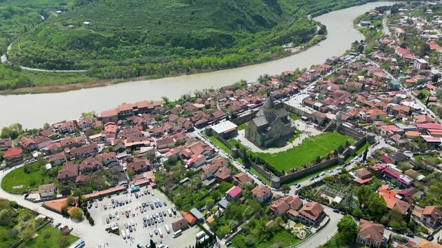 Aerial view of Mtskheta with red-roofed houses and the historic Svetitskhoveli Cathedral surrounded by river landscape. One of Georgia&rsquo;s oldest cities.