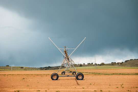 Irrigation sprinkler system on rural farmland under storm sky