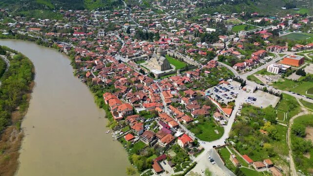 Aerial view of Mtskheta with red-roofed houses and the historic Svetitskhoveli Cathedral surrounded by river landscape. One of Georgia&rsquo;s oldest cities.