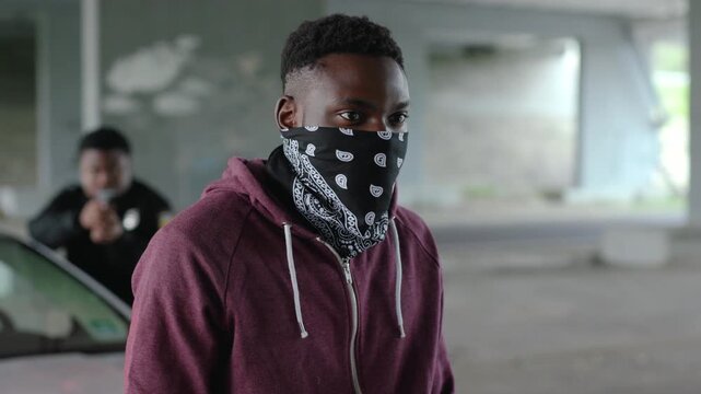 Young african american offender in mask stand in patrol car in handcuffs burglar crime hold danger gangster gun robber handgun illegal law outlaw arrest bad guy close up slow motion