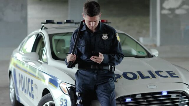 Policeman cops stand near patrol car use phone accepting emergence call enforcement talk officer police uniform auto safety security communication control policeman slow motion