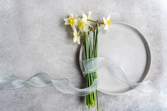 Minimal spring daffodil bouquet with ribbon on concrete