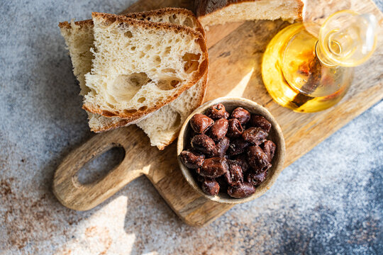 Rustic sourdough bread with olives and olive oil on board