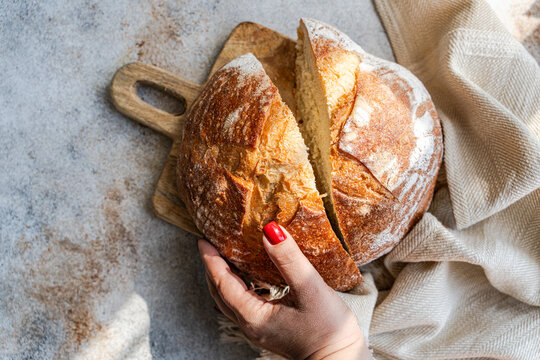 Rustic sourdough bread loaf being sliced on wooden board