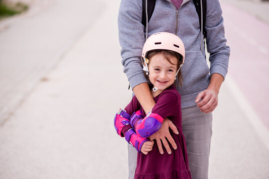 Father teaches daughter to roller skate outdoors
