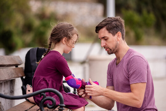 Father helping daughter with roller skating gear