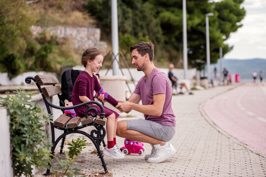 Father helping daughter with roller skating gear