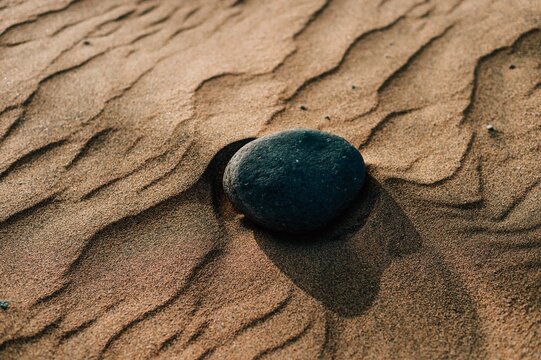 Sunlit volcanic stone on rippled sand in Maspalomas dune