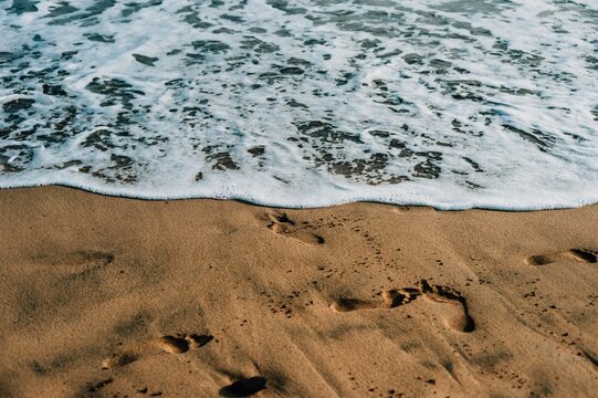 Ocean foam washing over sandy beach in Maspalomas