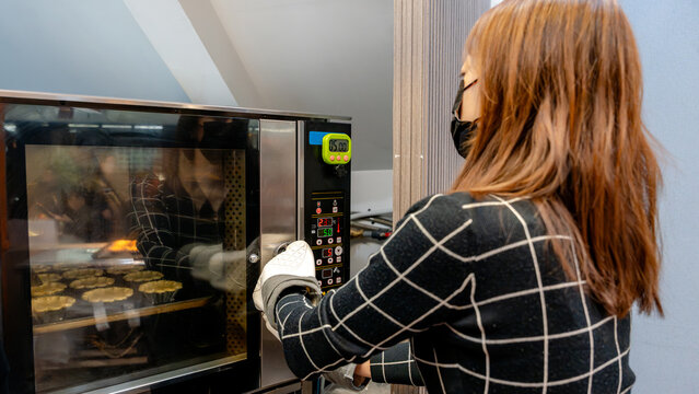 Taiwanese baker preparing egg tarts in a commercial oven