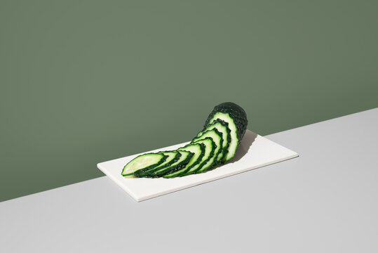 Fresh sliced cucumber arranged on white plate, minimal set