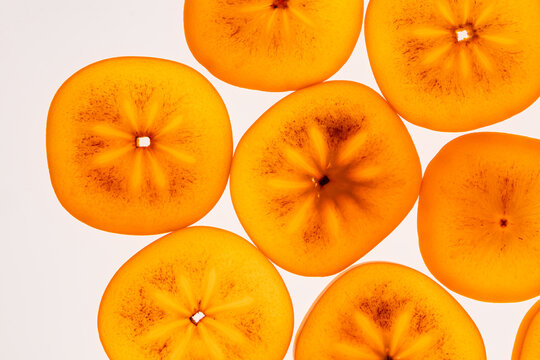 Sliced persimmon fruit background in bright orange