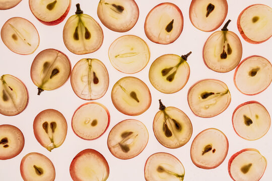 Pattern of halved grapes on white background flat lay