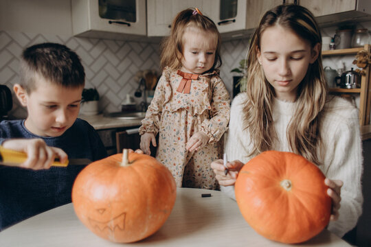 Siblings carving pumpkins at home for Halloween fun