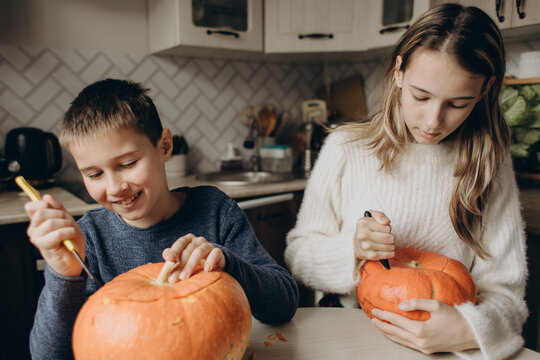 Children carving pumpkins at home for Halloween craft