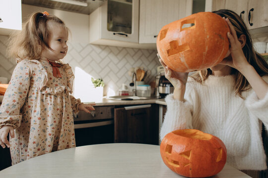 Sisters carving pumpkins in kitchen for Halloween at home