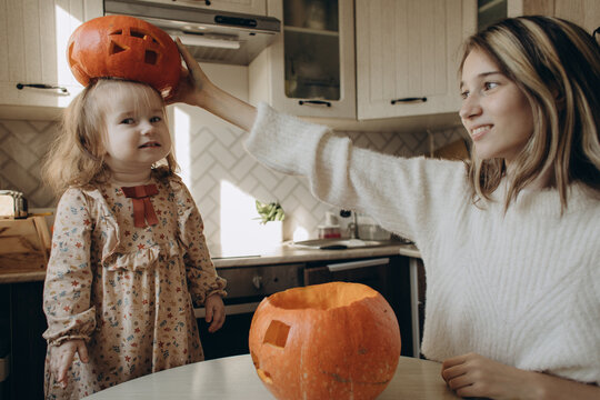 Siblings carving pumpkins together at home for Halloween