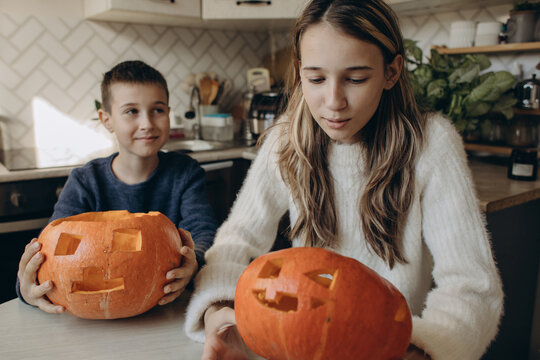 Brother and sister carving pumpkins at home for Halloween