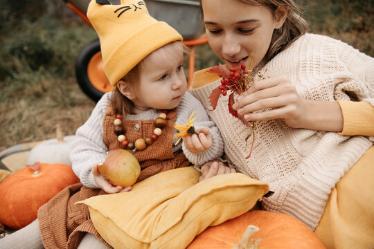Sisters enjoying pumpkins and autumn leaves outdoors