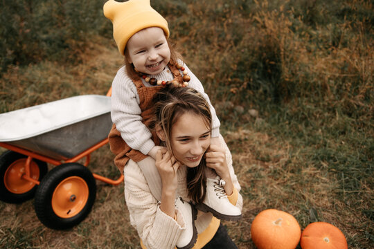 Sister giving younger girl a piggyback in autumn field