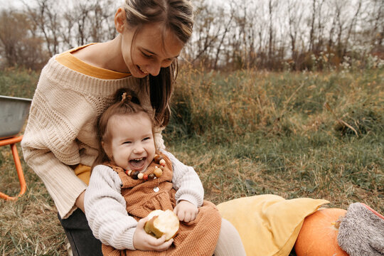 Sister holding a laughing girl with apple in autumn