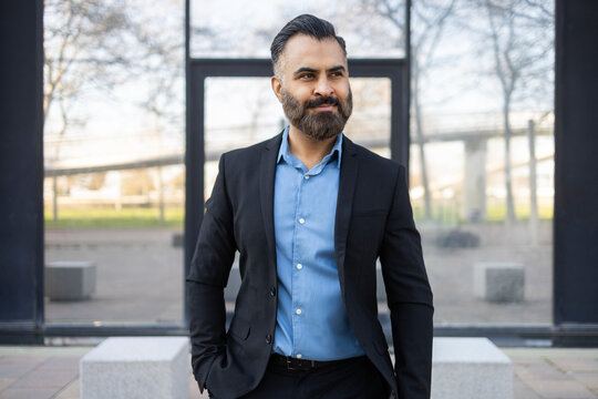 Confident Arab businessman in suit standing by modern office
