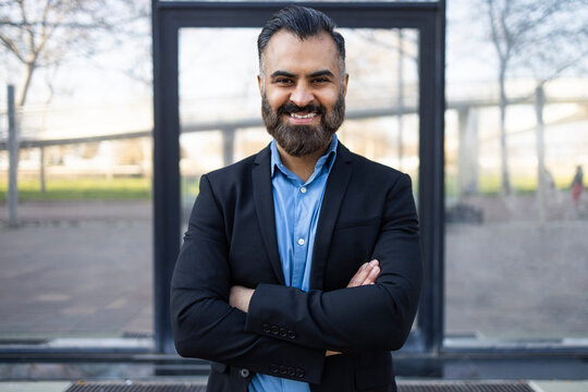 Confident Arab businessman smiling with arms crossed outdoors