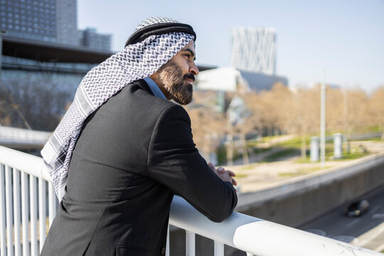 Arab businessman sheikh leaning on railing in cityscape