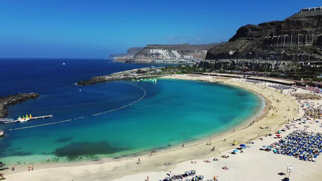 4K ProRes aerial of Amadores beach and coastline, people relaxing on sunny bay, natural grade Gran Canaria