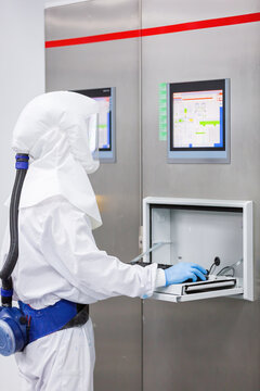Technician in cleanroom suit operating candy factory panel