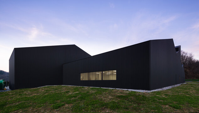 Modern black industrial building with glass windows at dusk