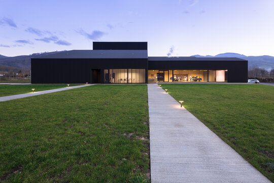 Modern candy factory exterior with lit walkway at dusk
