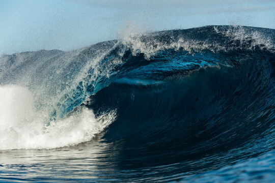 Powerful ocean wave curling with spray in blue seascape