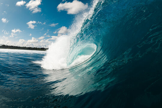 Powerful ocean wave curling into barrel near tropical shore